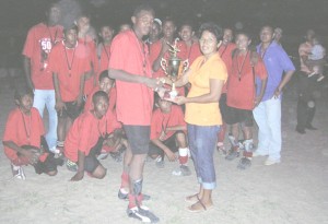 Theresa Torres (right) presents the winners trophy to the captain of the Central Rupununi team while the remainder of the side enjoy the moment.