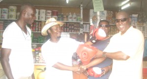 Businessman Roger Hinds (2nd left) receives the boxing gear from PS Steve Ninvalle, while looking on are sports promoter Feroze ‘Beeks’ Mootoo (2nd right with Shades) and Police Inspector Godfrey Williams.