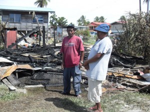 Sasenarine Bisoondial and his wife Indrawattie Mohabir stand in front  of the rubble that was once their home