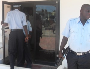 Police about to enter the Caricom Auto Sales  office, minutes after the bandits had fled.