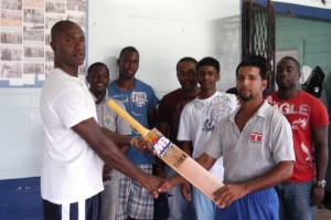 Malteenoes opening batsman Imran Hassan (right) receives the bat donated by Victor Dias from club-mate Neil Barry in the presence of team-mates yesterday.