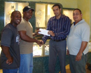 Kings Jewellery World Supervisor Rohandev Persaud  (2nd right) handing over the donation to Randolph Morgan in  the presence of Peter Green (right) and Mervin Moses.