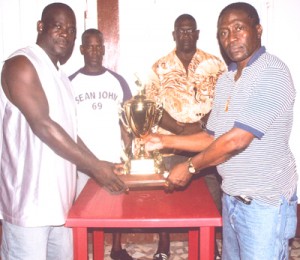 Murray (L) hands over the trophy up for  grabs, to Godfrey Samuels, President of the  West Demerara Domino Association.