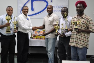 Bryden & Fernandes Inc. Marketing Coordinator Mark Kendall (2nd left) hands over the sponsorship cheque to GFA 3rd Vice President Jason Benjamin. Holding the trophies up for grabs, from left, are Rawl Davson of Bryden & Fernandes, Marlan Cole and Sampson Gilbert. 