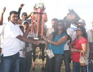 Its all smiles as a representative of the sponsors DDL presents the winning trophy to the two female reps of the Jumbo jet stable. Jumbo Joy with Paul Delph amount and Sequins are in the back ground.