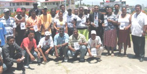 Ministers Irfaan Ali and Manzoor Nadir alongside recipients of house lots 