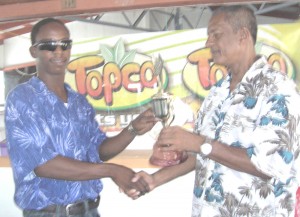 President of the Guyana Chess Federation, Errol Tiwari (right) presents Meusa with the winner’s trophy and check moments after he was declared winner of the DDL/Topco chess championships.