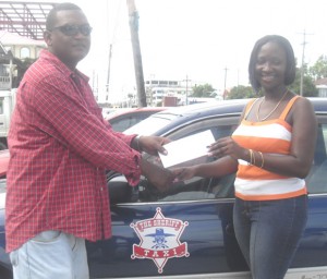 Antonetta Binns receives her cash prize from Gregory Toovey, Manager of the Sheriff Taxi Service.  