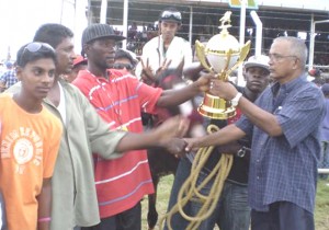 Mr James Muthoo of the Rumours racing stable at left collects the winning trophy from Alim Shaw of the Alim Shaw General Store.