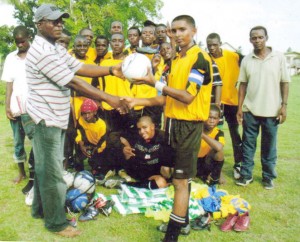  Founder of the New Amsterdam United Football Club Mason  Phillips (left) presents some of the equipment to U-17 captain  Antonio Beckham, while other members look on appreciatively.