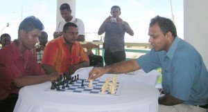 Minister Anthony makes the first move against junior chess aspirant, Sham Khan as National Champion Kriskal Persaud observes. 