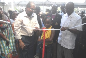  Minister Kellawan Lall and City Mayor Hamilton Green (right) assist this lass with the symbolic opening of the New Vendors’ Mall.