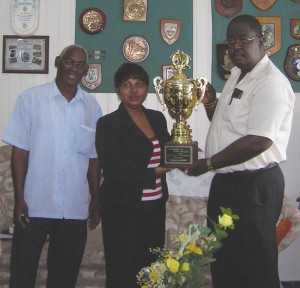 Macorp Sales Manager, Lyndon Bentick (right) hands over the trophy  for the first prize to Mayor Green's Secretary, Eva Orderson,  while Mr Green's personal assistant, John Green looks on.