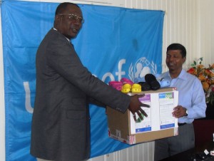 Minister of Education Shaik Baksh, right, receives the  donation from UNICEF representative, Suleiman Braiomoh. 