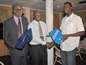  Alpha Goalkeeper Ronson Williams (right) collects his gift from Parliamentary Secretary Steve Ninvalle in the presence of club president Odinga Lumumba at their appreciating dinner at Water Chris hotel Saturday. 