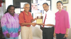 Mr. Christopher Ram (2nd left) hands over the plaque to Mr. Bish Panday in the presence of the Association’s Secretary, Ms. Grace McCalman (left) and Mrs. Panday. 