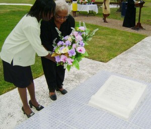 Mrs. Joyce Hoyte being assisted as she lays her floral tribute on  the occasion of the seventh death anniversary of her late husband