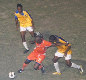 Conquerors’ Lester ‘Puppy’ Peters controls the ball and at the same  time staves off a challenge by Eagles’ Clive Nobrega as teammates  from either side watch closely. (Franklin Wilson photo)