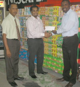 Jonathon Beepat (centre) hands over the sponsorship cheque to  GCA Head Mentore in the presence of former President Bish Panday.