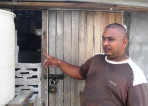 Devo Bicessar pointing at the entrance  the burglars took to enter his stall.  