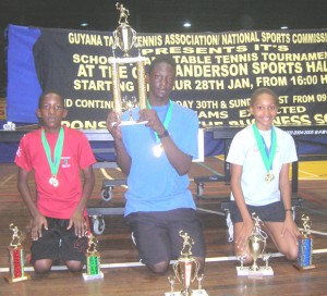 WE DID IT!!! Bishop’s High School’s, Denzil Duff (centre) holds aloft the overall Table Tennis Schools’ Teams Championship trophy in the presence of team-members, Chelsea Edghill (right) and Jamaal Duff, who proudly display the other replicas.