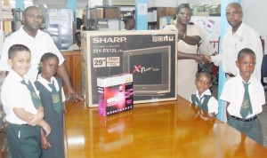 A GGMC representative hands over the television set and a DVD player to the Head Mistress of  St. Sidwell’s Primary, Donna Morgan.