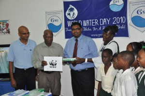 Minister Irfaan Ali, centre, receives educational materials to be used during a workshop  for school children in observance of World Water Day. The Head Teacher and students  of the St Sidwell’s Primary School are at right, while at left are GWI Chief Executive  Yuri Chandisingh and WWF Country Manager Dr Patrick Williams.  