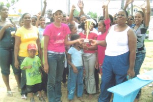 The two teams pose for a photo opportunity as Police team Captain Olive Tucker (right) presents the winning trophy to a representative of the Orphanage.