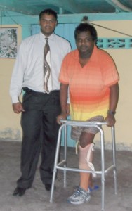 Anrood Ramrattan displays his new prostethic leg which was presented by local steering committee member Rasheed Baksh on behalf of the Enterprise Support Group USA inc.