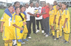 Flights of Hope Executive, Praimnauth Mohanlall (centre, left) hands over the samples of gear to Region Nine’s Women Football Manager, Brian Rodrigues while Flights of Hope founder, Orlando Charles (second left, centre), other officials and Region Nine’s Women Football team share the moment.