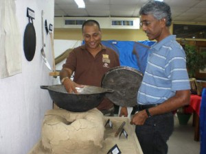 Alim Hosein, Head of UG’s Department of Language  and Cultural Studies (right) and art lecturer Philbert Gajadhar  looking at one of the exhibits yesterday at UG.