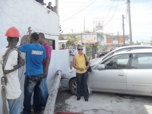 Narrow escape! Simone Baburam stands near to the utility  pole which almost killed her, as a GPL crew removes the wires 