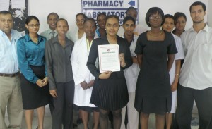 Dr Pheona Mohamed-Rambaran displays the certificate.  She is flanked by health and GNBS officials. 