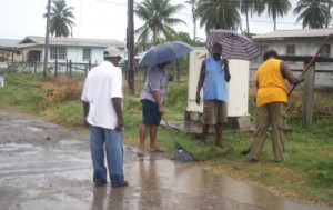 Residents of Melanie Damishana brave the rains to clean up their community.   