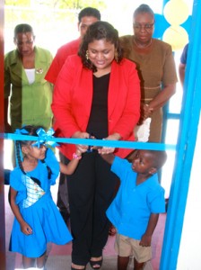 Minister Manickchand assisted by two pupils of the school cuts the ceremonial ribbon. 