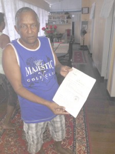 Seelall Salikram holds up a copy of his home’s registration 