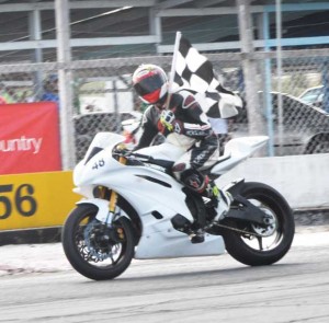 Superbike champion Matthew Vieira acknowledges the applause of the fans with the chequered flag following one of his victories.