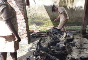 A Fire Service official  inspects what is left  of the motorcycle.   