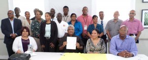 GECOM Chairman Steve Surujbally (centre) holds up a copy of the Code of Conduct after it was signed by high-ranking members of several local media houses. With him are some participants. 