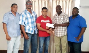 Dinar Trading Manager Vishal Rampersaud handing over his company’s Cheque to Aubrey ‘Shanghai’ Major in the presence of other staff.