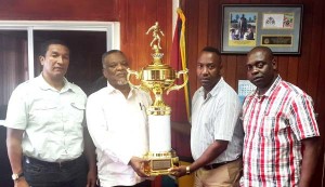 Frank ‘English’ Parris receives the trophy from PM Hinds in the presence of Kashif Muhammad (left) and Aubrey ‘Shanghai’ Major. 