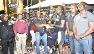 Banks DIH Area Supervisor Clive Pellew (3rd left) hands over the winning trophy and prize money to BV ‘A’ Captain Delroy Deen in the presence of Guinness Brand Manager Lee Baptiste (right), Petra Organisation Co-Director Troy Mendonca (left), officials and teammates.