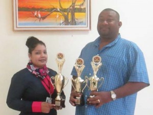 RHTYSC Secretary/CEO Hilbert Foster receives trophies from Bibi Khan of the Berbice River Bridge Company.