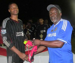 Canada-based Edward ‘Screw’ Richmond member James ‘Gads’ Dennis (right) handing over a new pair of football boots to Top Goal Scorer Shane Lucky of Christianburg Wismar Secondary School.