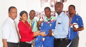 Ms. Melinda Sammy, Accounts Executive of P & P Insurance handing over some of the uniforms to Mr. Bishop in the presence of Mr. Bish Panday (left) and other representatives of the school.