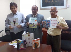 The Indian High Commissioner, along with S.M. Joshi, Political officer (left) and a representative from the Indian Cultural Centre (right) with several books on yoga that will be on display.