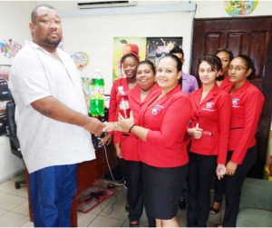 Maria Chin of the Guyana Beverage Company hands over donation to the club.