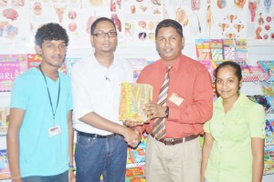 Mr Yudesh Armogan, Manager of Office Express hands over a gate prize to BCB Executive Vicky Bharosay in the presence of other staff members. 