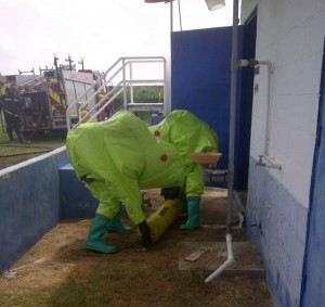 Two officials from the Guyana Fire Service Hazmat team removing the cylinder