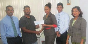 Customer Service Representative Ms. Lisa Balprashad presents the cheque to RHTY&SC Member Mark Papannah in the presence of staff members, Harry Dass Ghaness, Seema Brijemal and Christopher Phagoo.